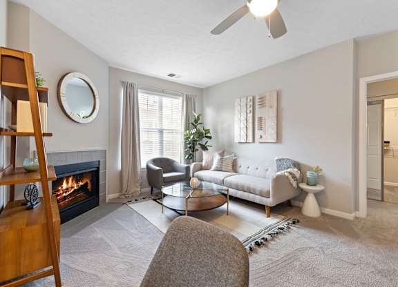 Living room with a grey couch at Sand Creek Woods Apartments, Fishers, IN