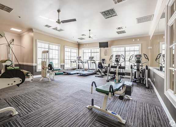 A spacious gym with a variety of equipment including treadmills, exercise bikes, and weight machines.