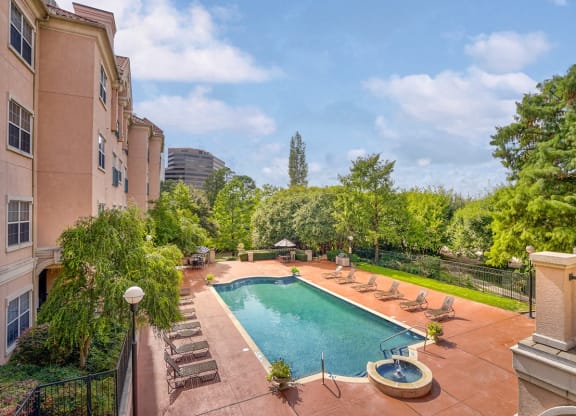 a swimming pool with lounge chairs and a building with trees