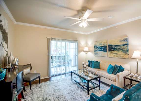 A living room with a blue couch and a ceiling fan.