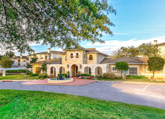 A large house with a circular driveway and a fountain in the middle.