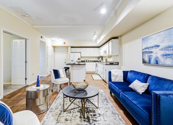 a living room with a blue couch and a kitchen in the background