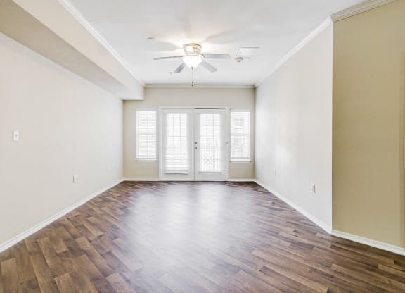 an empty living room with wood flooring and a ceiling fan