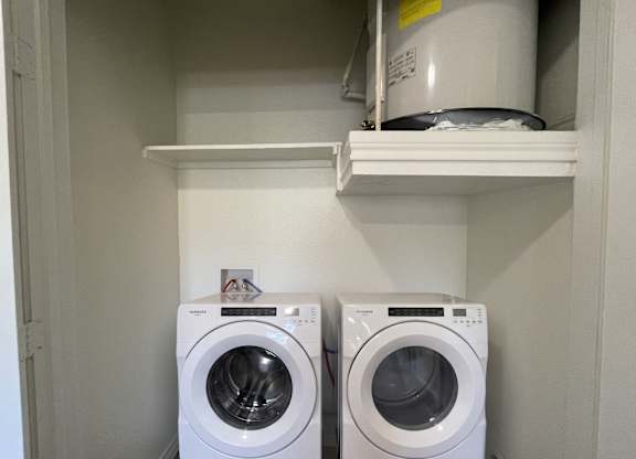 Two white washing machines in a small laundry room.