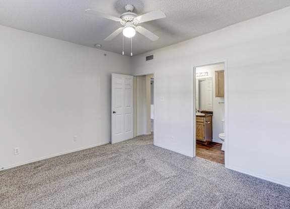 A room with a ceiling fan and carpeted floor.