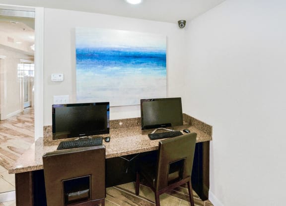 a computer desk with two monitors and two chairs