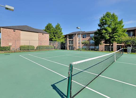 A tennis court with a net and a building in the background.