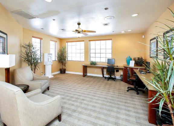 a living room with couches and chairs and a desk with a computer