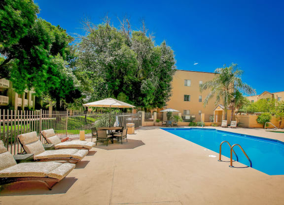a swimming pool with lounge chairs and umbrellas next to a building