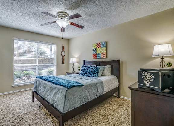 A bedroom with a bed, nightstand, and window.