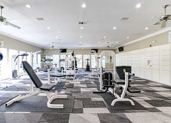 A gym with a variety of equipment including treadmills, weights, and exercise machines.