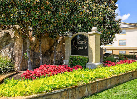 A sign that says Tuscany Square stands in front of a building.