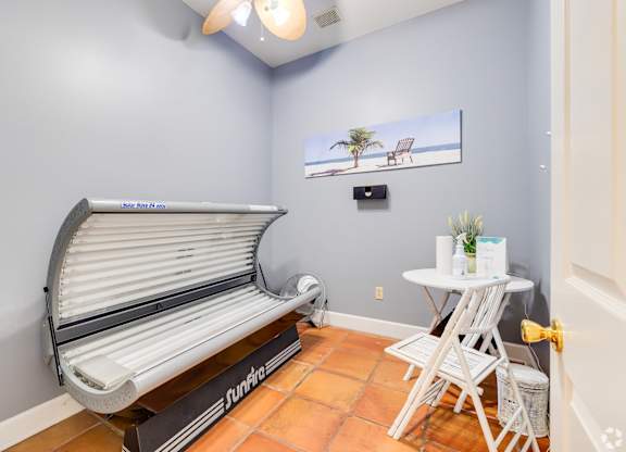A tanning bed is in a room with a small table and chairs.