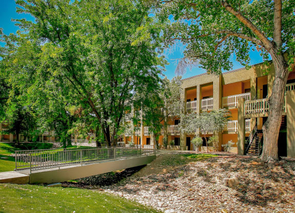 a bridge over a pond in front of a building with trees