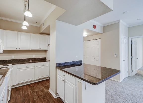 an empty kitchen with white cabinets and granite counter tops