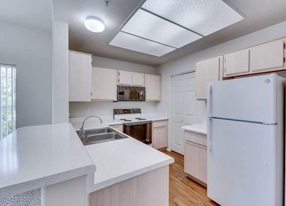 A white refrigerator is in the corner of a kitchen.