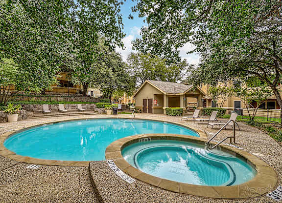 A swimming pool surrounded by trees and a house in the background.