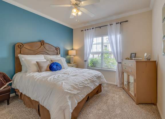 A bedroom with a bed, dresser, and window.
