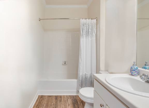 A white bathroom with a toilet, sink, and shower.