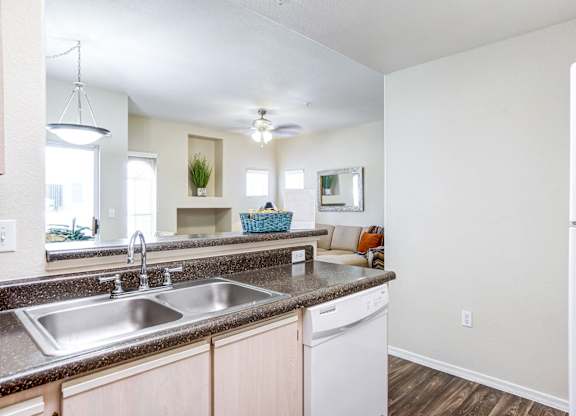 A kitchen with a white fridge and a stainless steel sink.