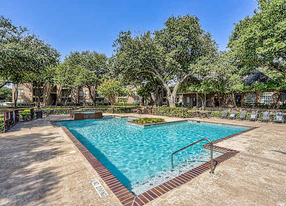A large outdoor pool surrounded by trees and a fence.