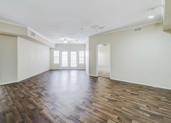 an empty living room with a hard wood floor and white walls