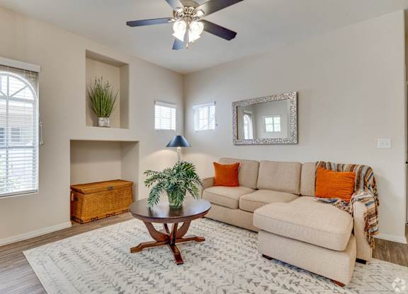 A living room with a beige couch, a wooden coffee table, and a ceiling fan.