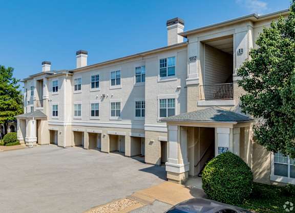 A large, multi-story apartment building with a parking lot in front.