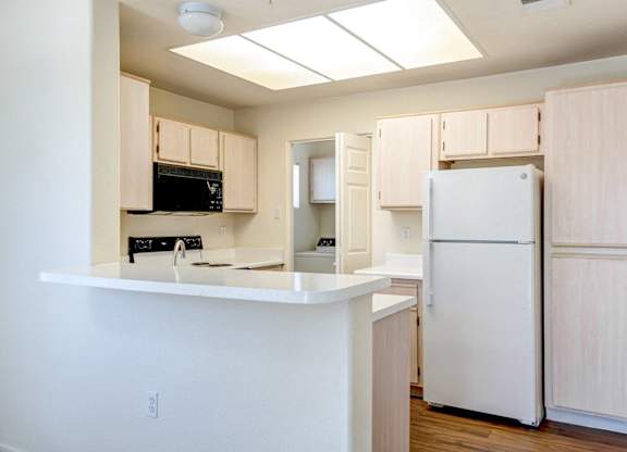 A kitchen with a white refrigerator and cabinets.