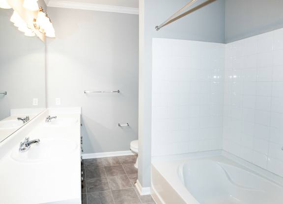 A white bathroom with a tub, sink, and toilet.