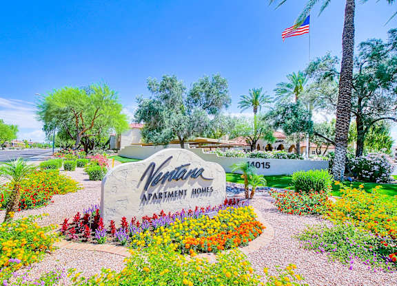A sign for a Vine Park Apartment Homes is surrounded by flowers.