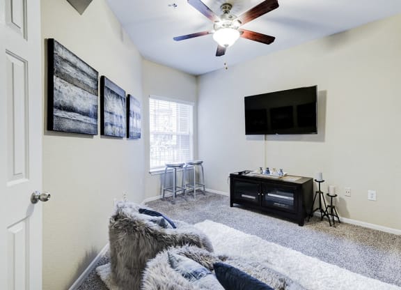 a living room with a ceiling fan and a tv