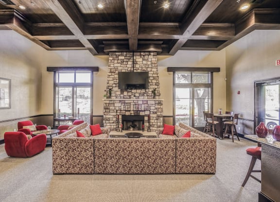 Large community clubhouse with a large couch overlooking a fireplace at Cypress Lake at Stonebriar in Frisco, TX!