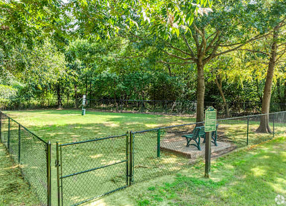 A green sign is in front of a fence and a tree.