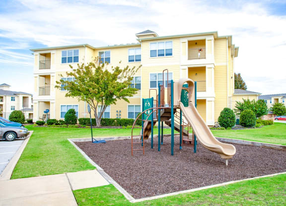 a playground with a slide in front of an apartment building