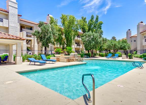 A swimming pool surrounded by a fence and chairs.