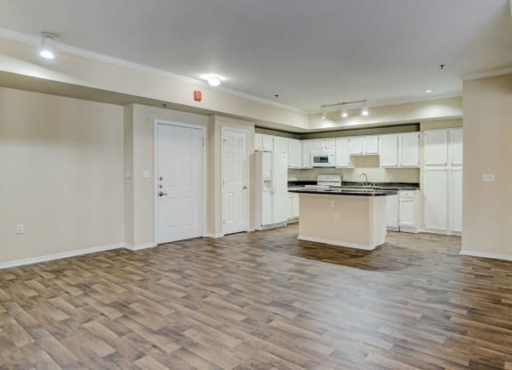 an empty living room and kitchen with a counter top in the middle