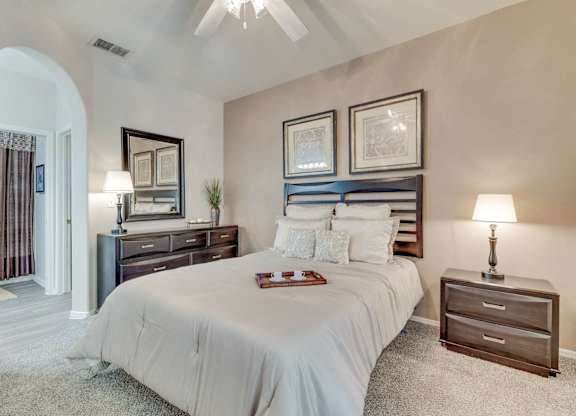 A bedroom with a large bed, a dresser, and a nightstand.