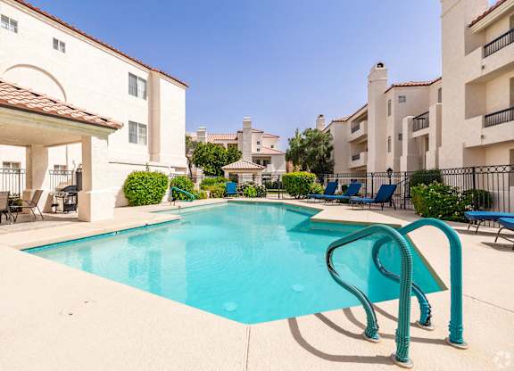 A swimming pool with a diving board in front of apartment buildings.