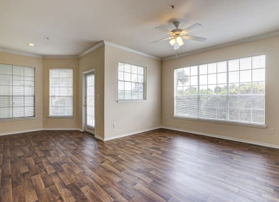 Bright living and dining rooms with large windows and wood floring at Turnberry Isle Apartments in Dallas, TX.
