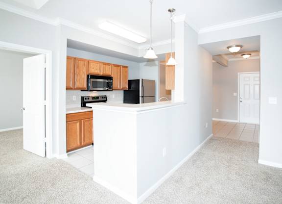 A kitchen with white walls and wooden cabinets.