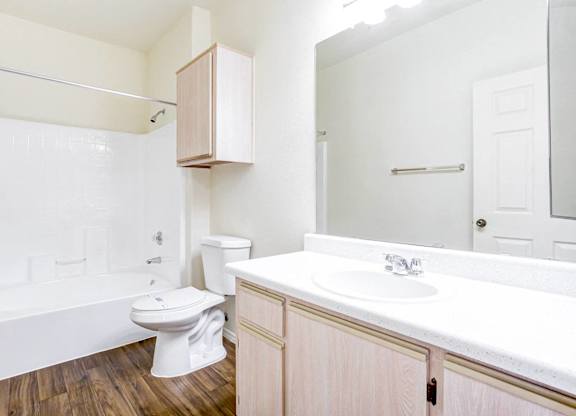 A white toilet sits in a bathroom next to a white sink.