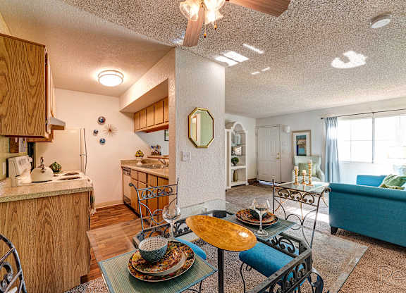 A dining table with a yellow plate on it is in the middle of a kitchen and living room.
