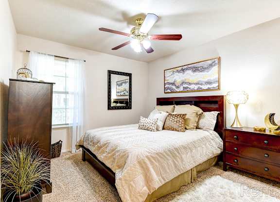 A bedroom with a bed, dresser, and ceiling fan.