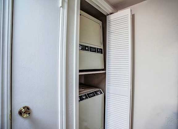 A white door with a handle is open to reveal a white fridge and freezer.