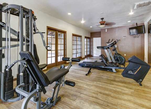 A home gym with a variety of equipment including a treadmill, weights, and a bench press.