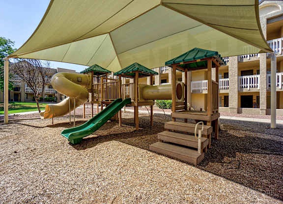 A playground with a green slide and a yellow and green canopy.
