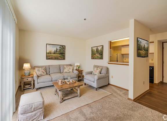 A living room with a grey couch, a chair, a coffee table, and pictures on the wall.