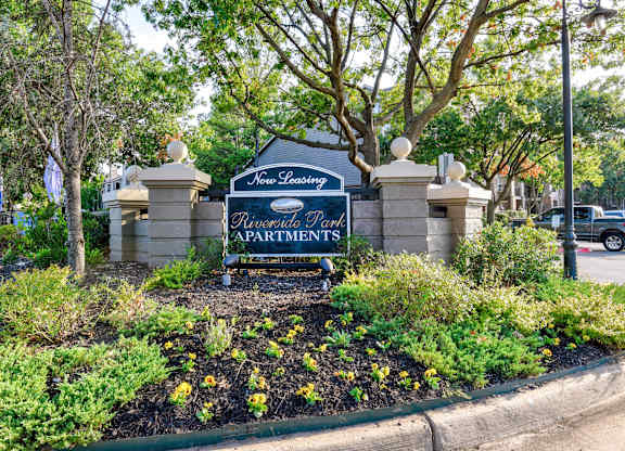 A sign for Bouverie Park Apartments is surrounded by flowers and trees.