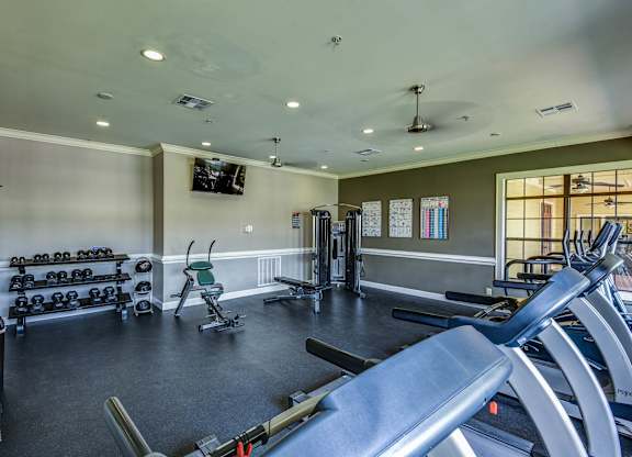 A gym with a variety of equipment including treadmills, weights, and exercise machines.